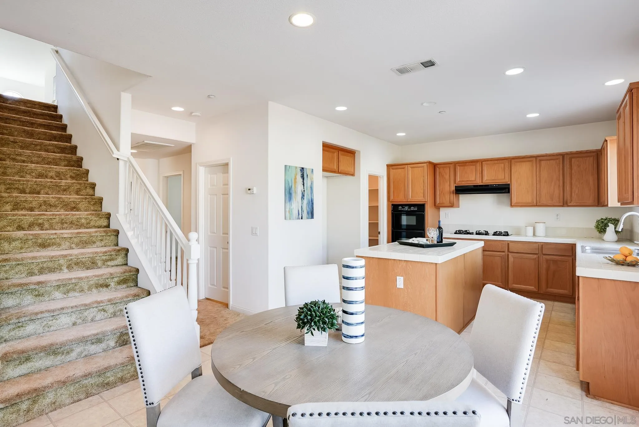 17048 Ralphs Ranch Road San Diego, CA 92127 - Photo 11 of 26 a kitchen with stainless steel appliances granite countertop a dining table chairs and a refrigerator