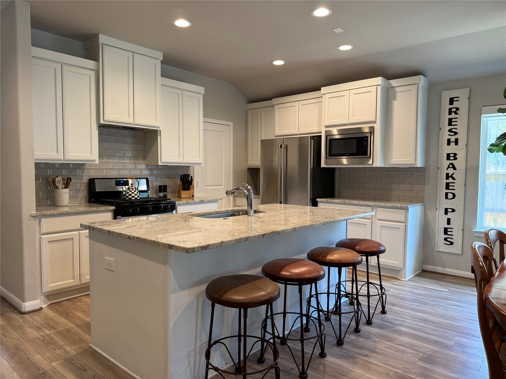 2336 Hagerman Road Conroe, TX 77384 - Photo 15 of 35 a kitchen with stainless steel appliances granite countertop a stove top oven a refrigerator a sink and a dining table with wooden floor