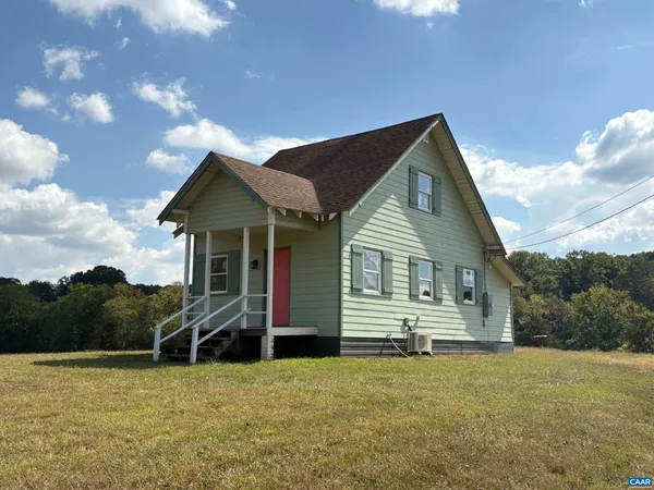 a front view of house with yard and trees in the background