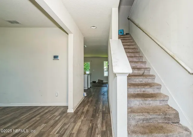 a view of a hallway with wooden floor and staircase