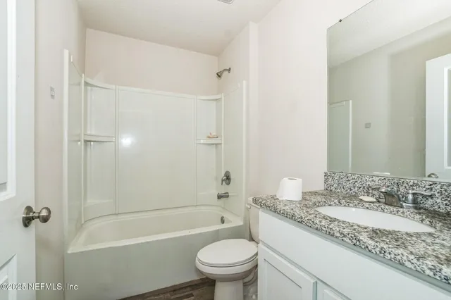 a bathroom with a granite countertop sink a toilet and shower