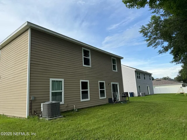 a backyard of a house with potted plants and large tree