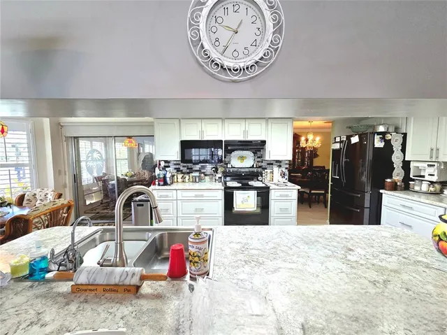 a kitchen with stainless steel appliances kitchen island granite countertop a refrigerator and a sink