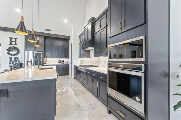 a large kitchen with stainless steel appliances kitchen island granite countertop a sink and cabinets