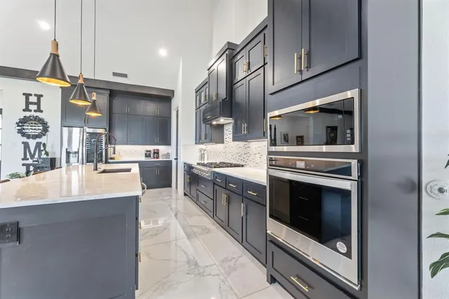 a large kitchen with stainless steel appliances kitchen island granite countertop a sink and cabinets