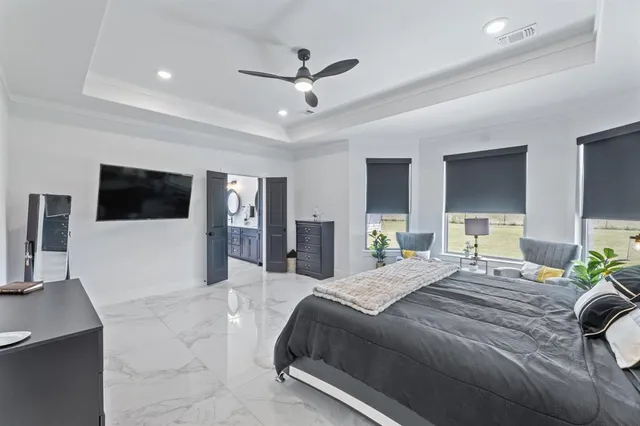 a bedroom with a large bed a flat screen tv and a large window