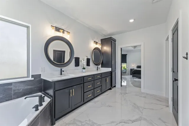 a spacious bathroom with a double vanity sink a mirror and bathtub