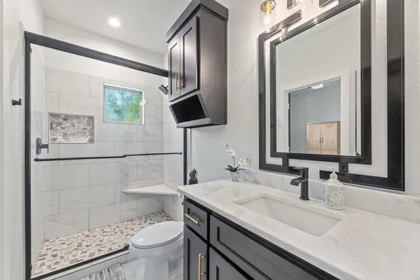 a bathroom with a granite countertop sink toilet and mirror