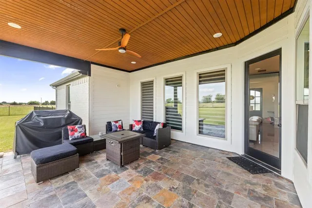 a living room with furniture a flat screen tv and floor to ceiling window