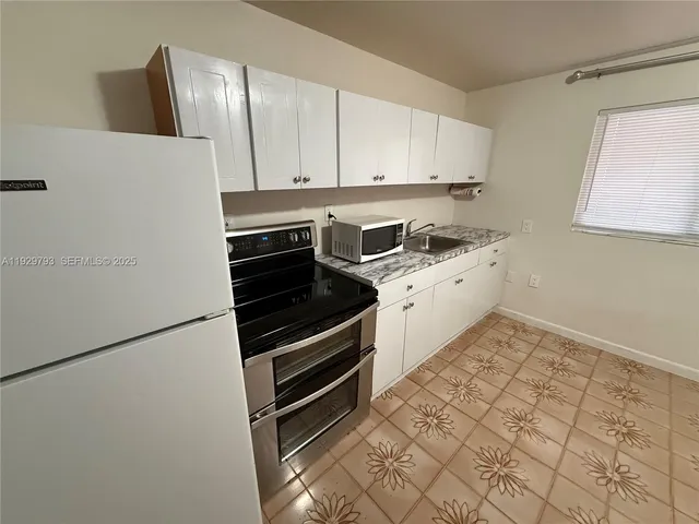 a kitchen with granite countertop a refrigerator and a stove top oven