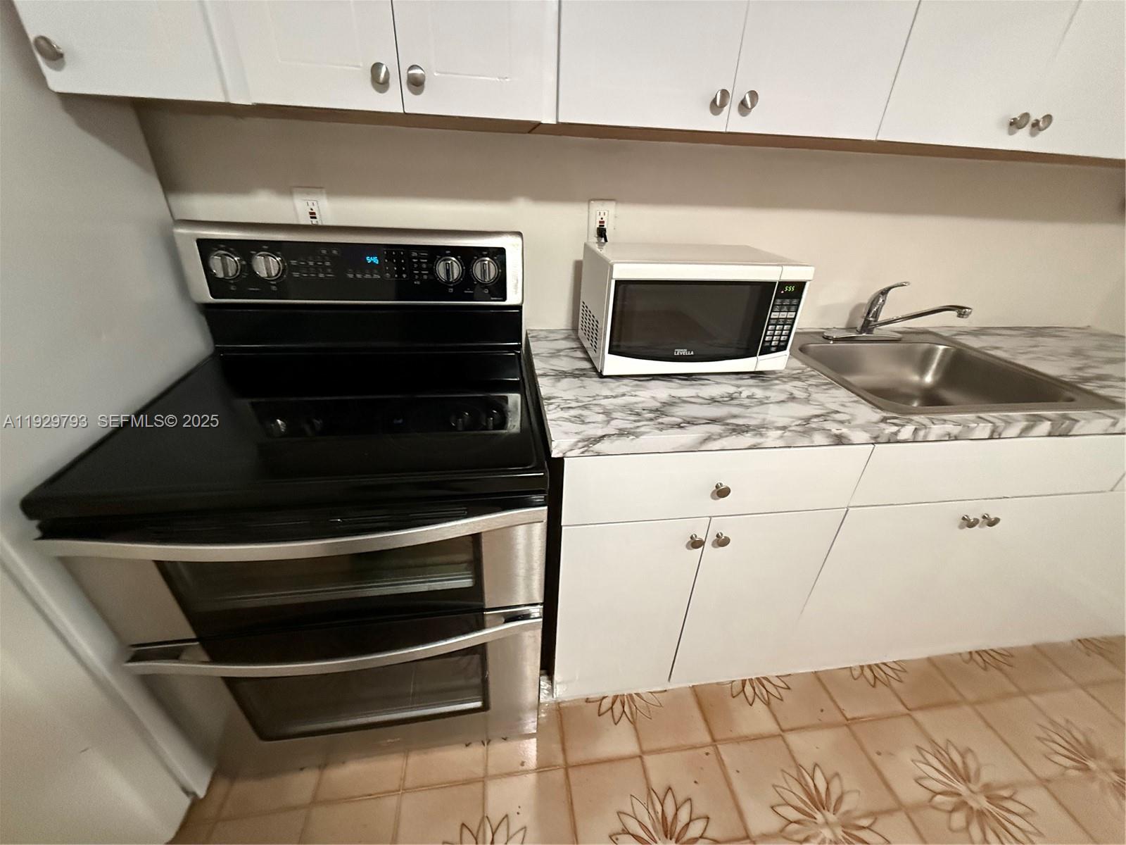 6765 Southwest 19th Street, Unit BACK Miami, FL 33155 - Photo 2 of 7 a kitchen with a stove and white cabinets