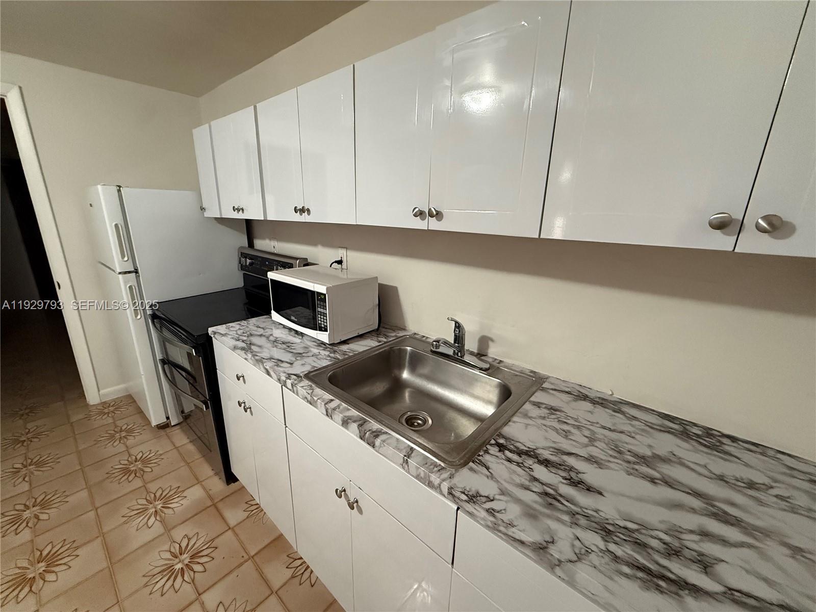 6765 Southwest 19th Street, Unit BACK Miami, FL 33155 - Photo 3 of 7 a kitchen with a sink a stove and cabinets