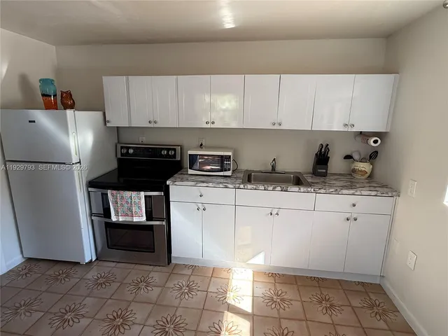 a kitchen with granite countertop a refrigerator sink and cabinets