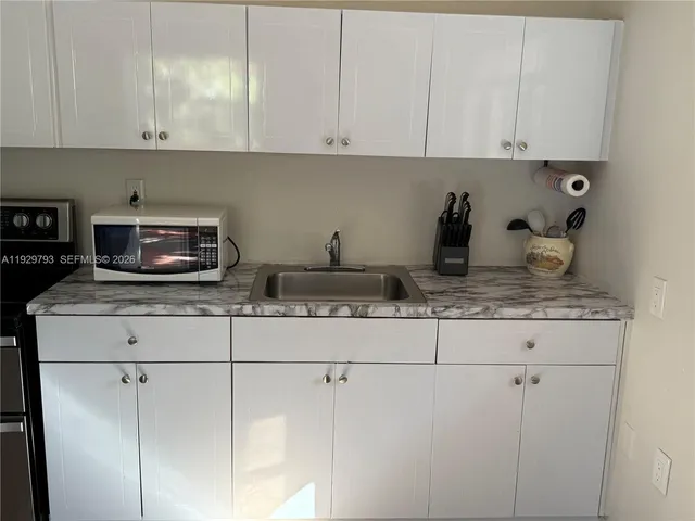 a kitchen with granite countertop white cabinets and a stainless steel appliances