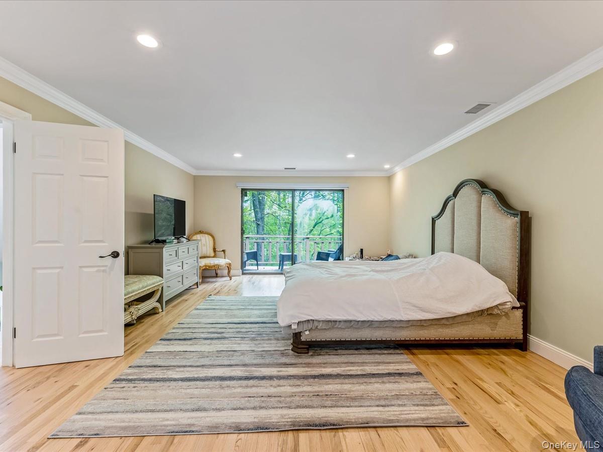 54 Harvard Road, Unit 54 Manhasset, NY 11030 - Photo 22 of 48 a spacious bedroom with a large bed and wooden floor