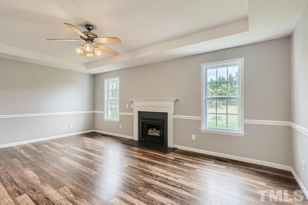 386 Rosa Circle Willow Spring, NC 27592 - Photo 5 of 27 an empty room with windows fireplace and fan