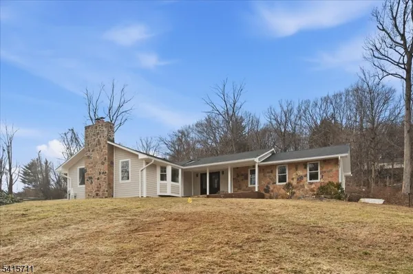 a front view of house with yard and trees in the background