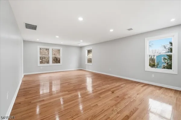 a view of an empty room with window and wooden floor