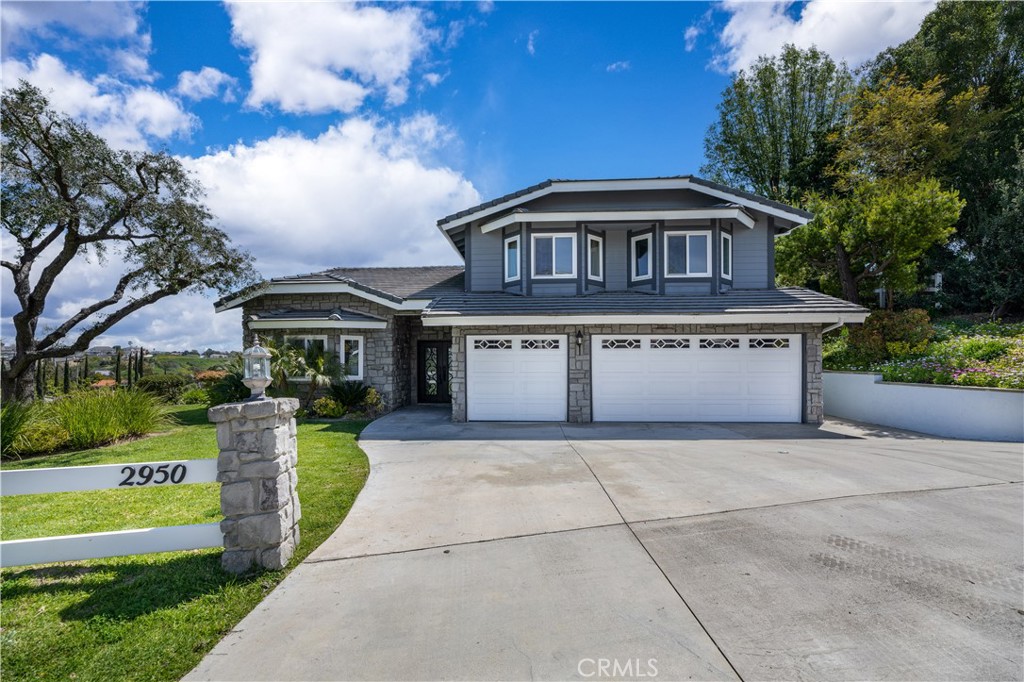 a view of a house with a yard plants and large tree
