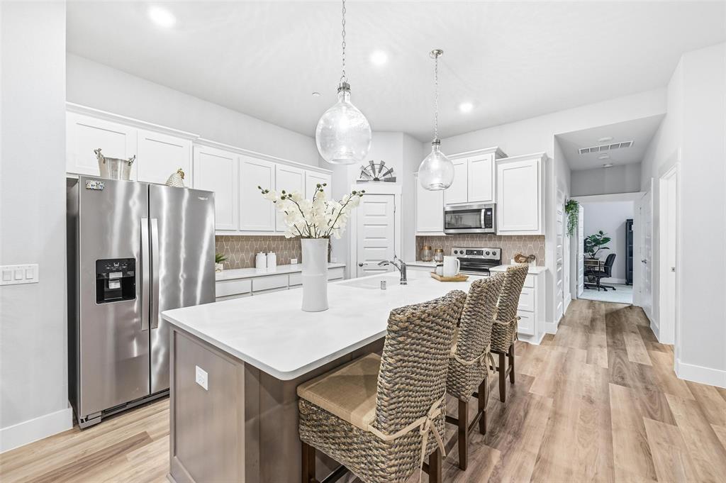 7236 Calistoga Lane Grand Prairie, TX 75054 - Photo 15 of 40 a kitchen with stainless steel appliances kitchen island granite countertop a refrigerator a stove a sink a dining table and chairs with wooden floor
