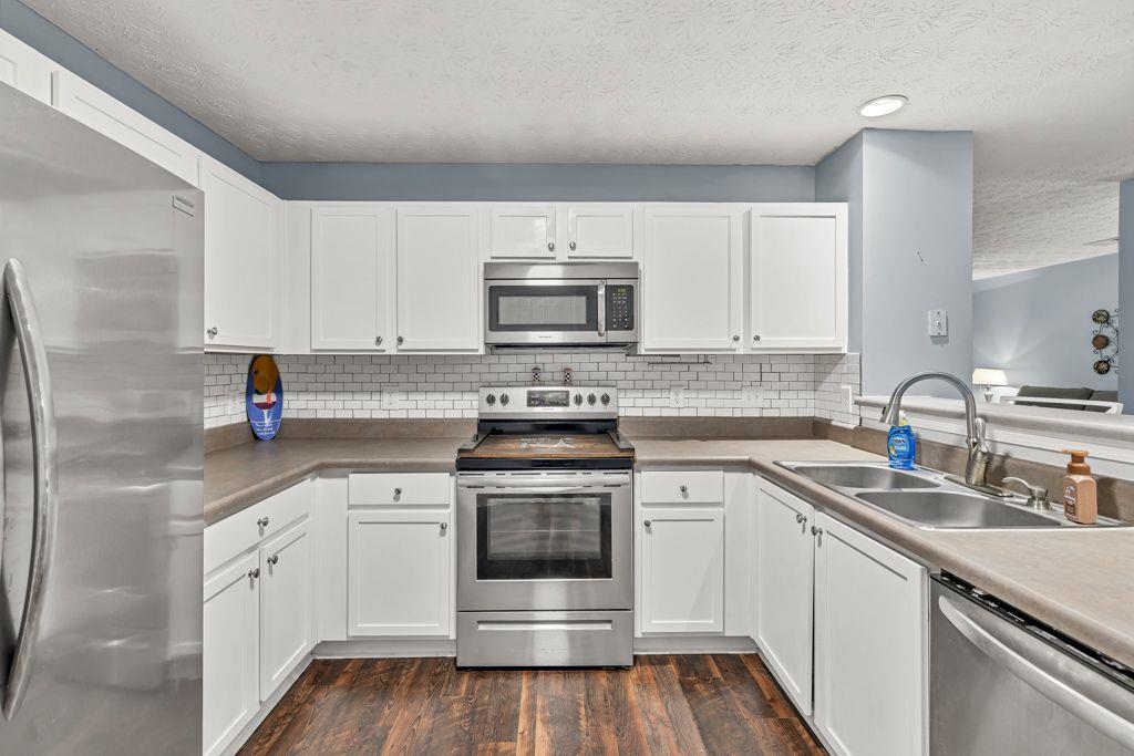 233 Tara Commons Walk Loganville, GA 30052 - Photo 14 of 52 a kitchen with granite countertop white cabinets and white appliances