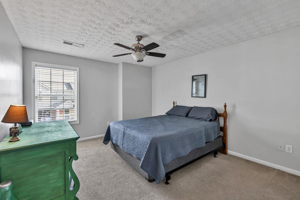 233 Tara Commons Walk Loganville, GA 30052 - Photo 36 of 52 a spacious bedroom with a bed chandelier and a window