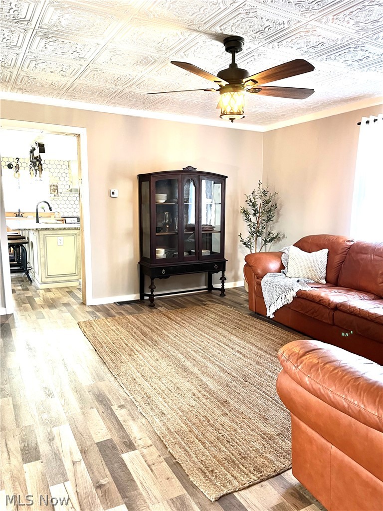 12972 Gilmore Road Southeast Port Washington, OH 43837 - Photo 7 of 50 Living room featuring light wood-style flooring, a ceiling fan, an ornate ceiling, and crown molding