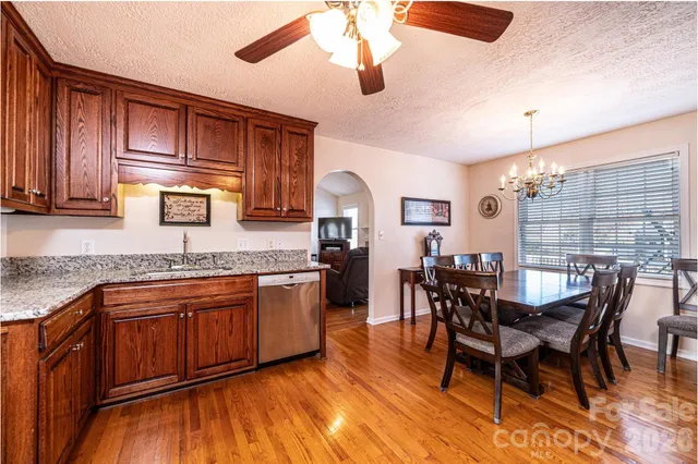 a kitchen with stainless steel appliances granite countertop wooden cabinets a dining table and chairs