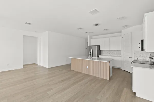a room with stainless steel appliances wooden floors and white walls