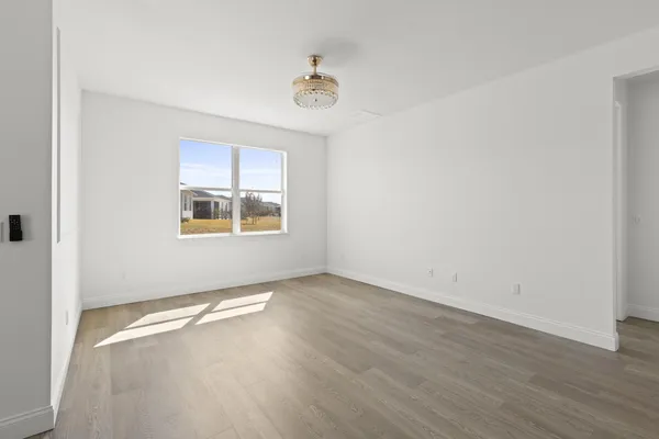 an empty room with wooden floor cabinet and windows