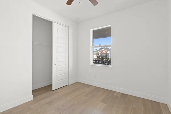 an empty room with wooden floor and windows