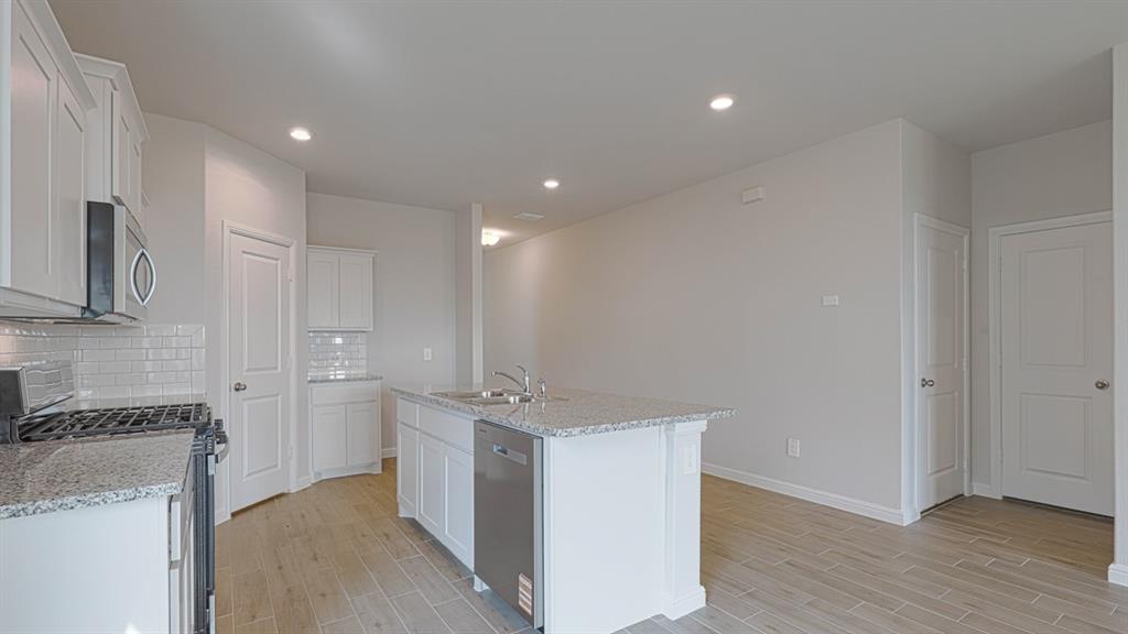 a view of a kitchen with a sink and dishwasher a refrigerator with wooden floor