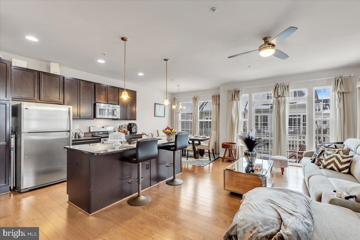 49 Steeplechase Drive La Plata, MD 20646 - Photo 9 of 27 a kitchen with stainless steel appliances kitchen island granite countertop a refrigerator a sink dishwasher a dining table and chairs with wooden floor