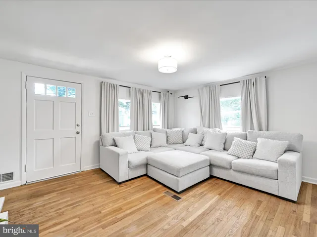 a living room with couches and white cabinets with wooden floor