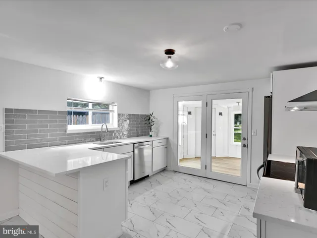 a large white kitchen with stainless steel appliances granite countertop a sink and dishwasher