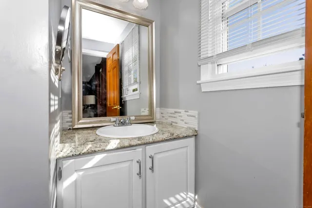a bathroom with a granite countertop sink and a mirror