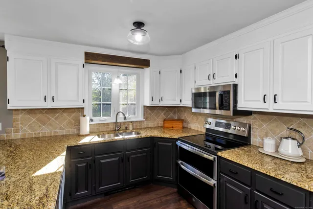 a kitchen with granite countertop a sink cabinets and stainless steel appliances