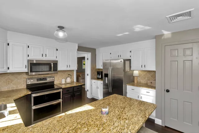 a kitchen with stainless steel appliances kitchen island granite countertop a refrigerator and a stove top oven