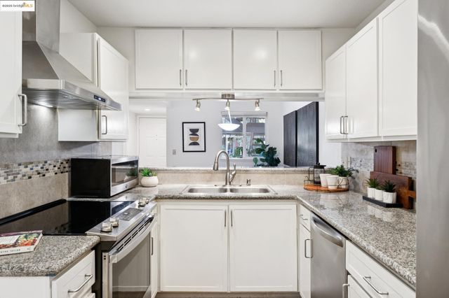 a kitchen with granite countertop a sink stove and cabinets