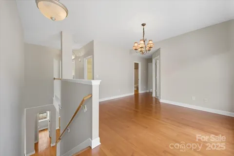 a view of a hallway with wooden floor and a chandelier