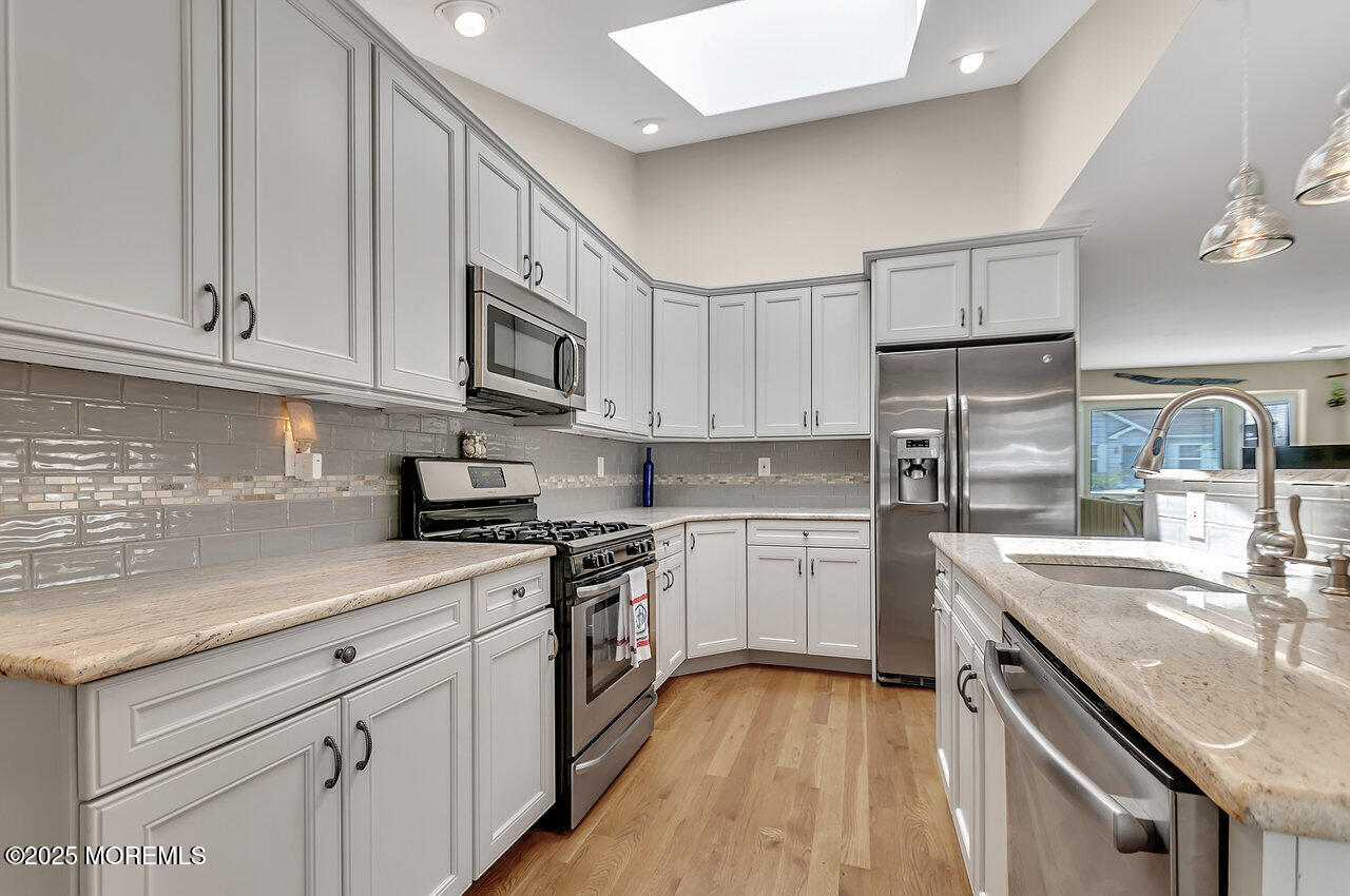 660 Drum Point Road Brick, NJ 08723 - Photo 3 of 26 a kitchen with kitchen island granite countertop a sink stainless steel appliances and white cabinets