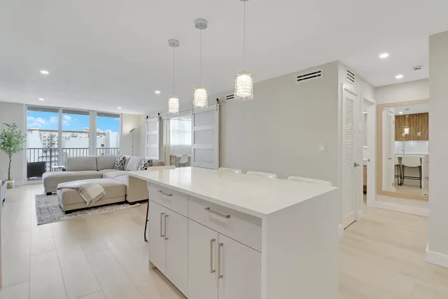 a large white kitchen with a white center island and stainless steel appliances