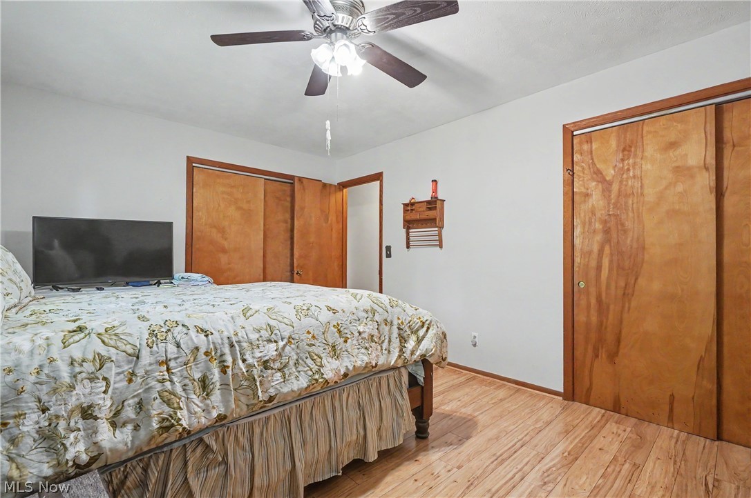 4250 Herr Fieldhouse Road Southington, OH 44470 - Photo 14 of 50 Bedroom featuring wood-finish flooring, a ceiling fan with integrated lighting, and two sets of sliding wood doors