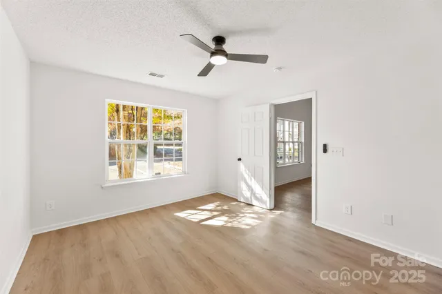 a view of empty room with wooden floor and fan