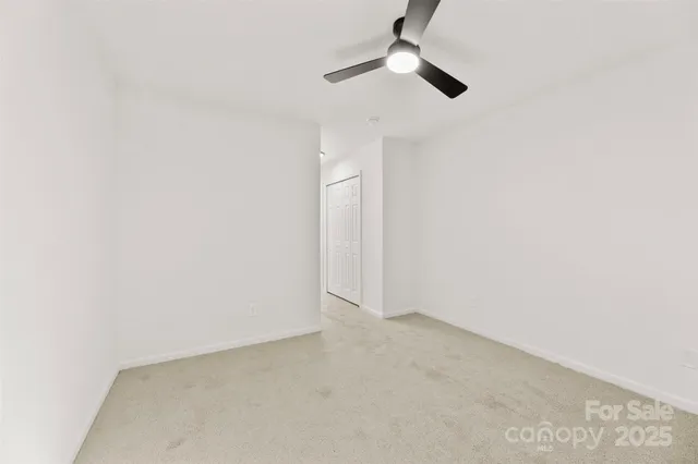 an empty room with a ceiling fan and a window