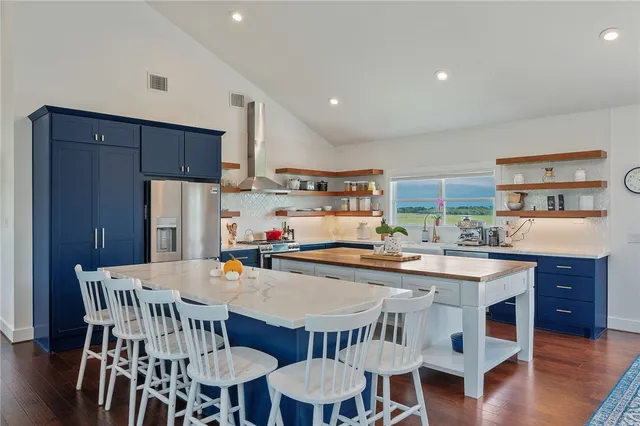 a kitchen with stainless steel appliances a dining table chairs and wooden floor