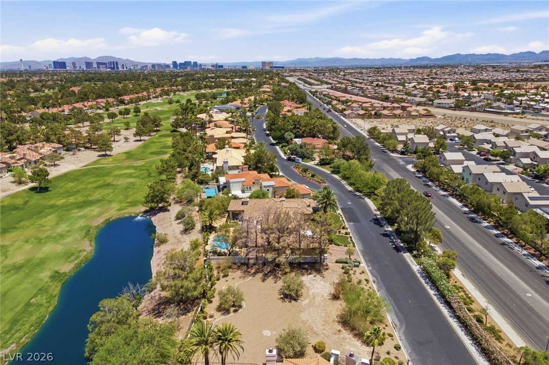 20 Innisbrook Avenue Las Vegas, NV 89113 - Photo 15 of 39 An aerial perspective reveals a serene golf course bordering residential streets, set against a distant city skyline.