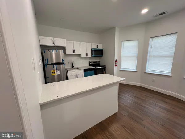 a living room with stainless steel appliances a refrigerator a stove a microwave and cabinets