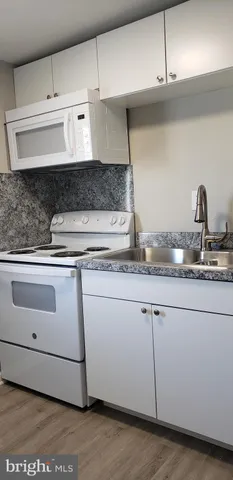 a kitchen with granite countertop white cabinets and white appliances