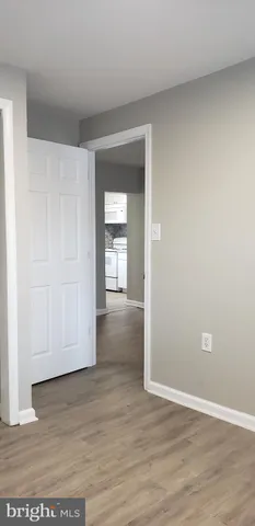 a view of an empty room with wooden floor and closet